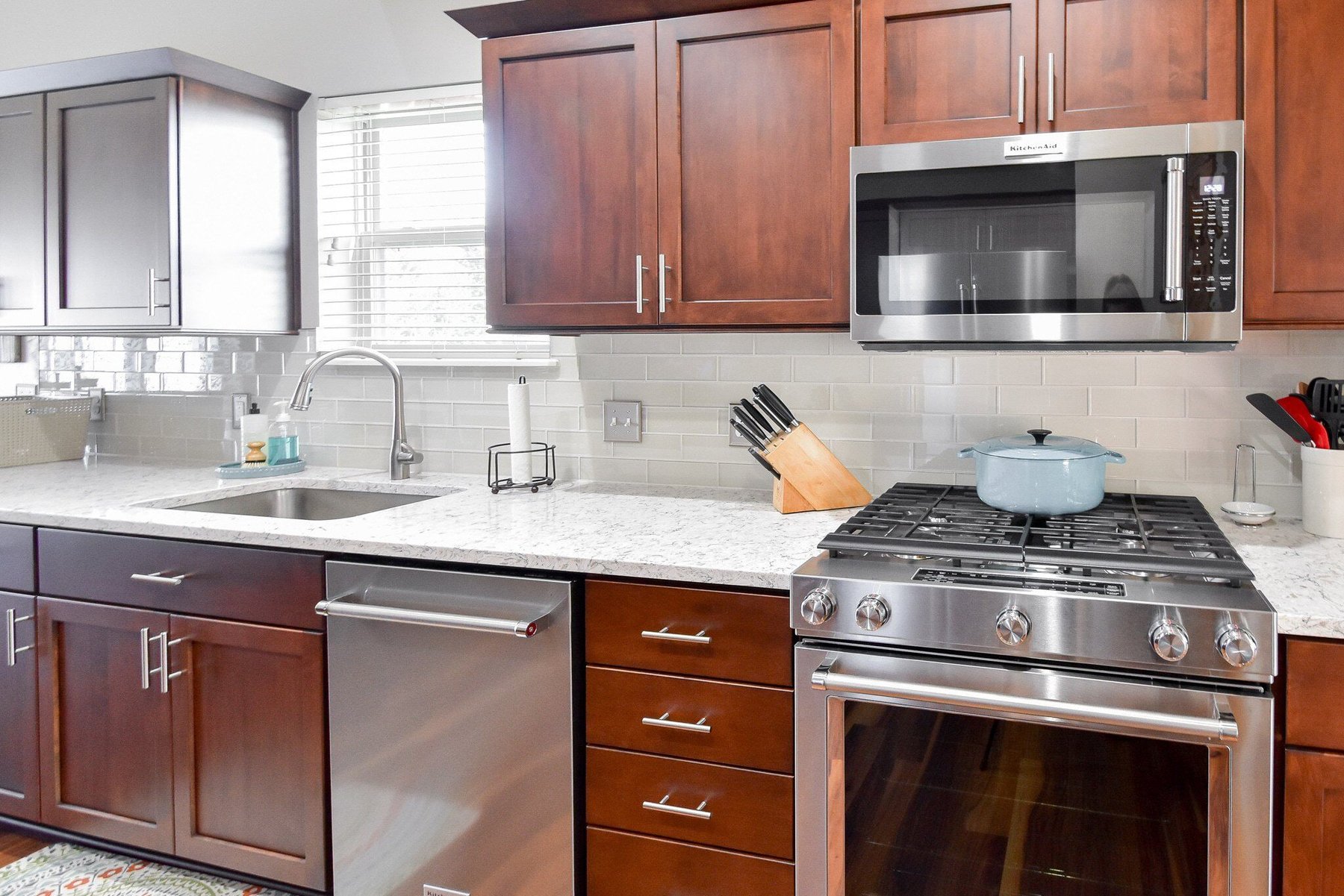 Kitchen with refaced cherry wood cabinet doors and a stone countertop