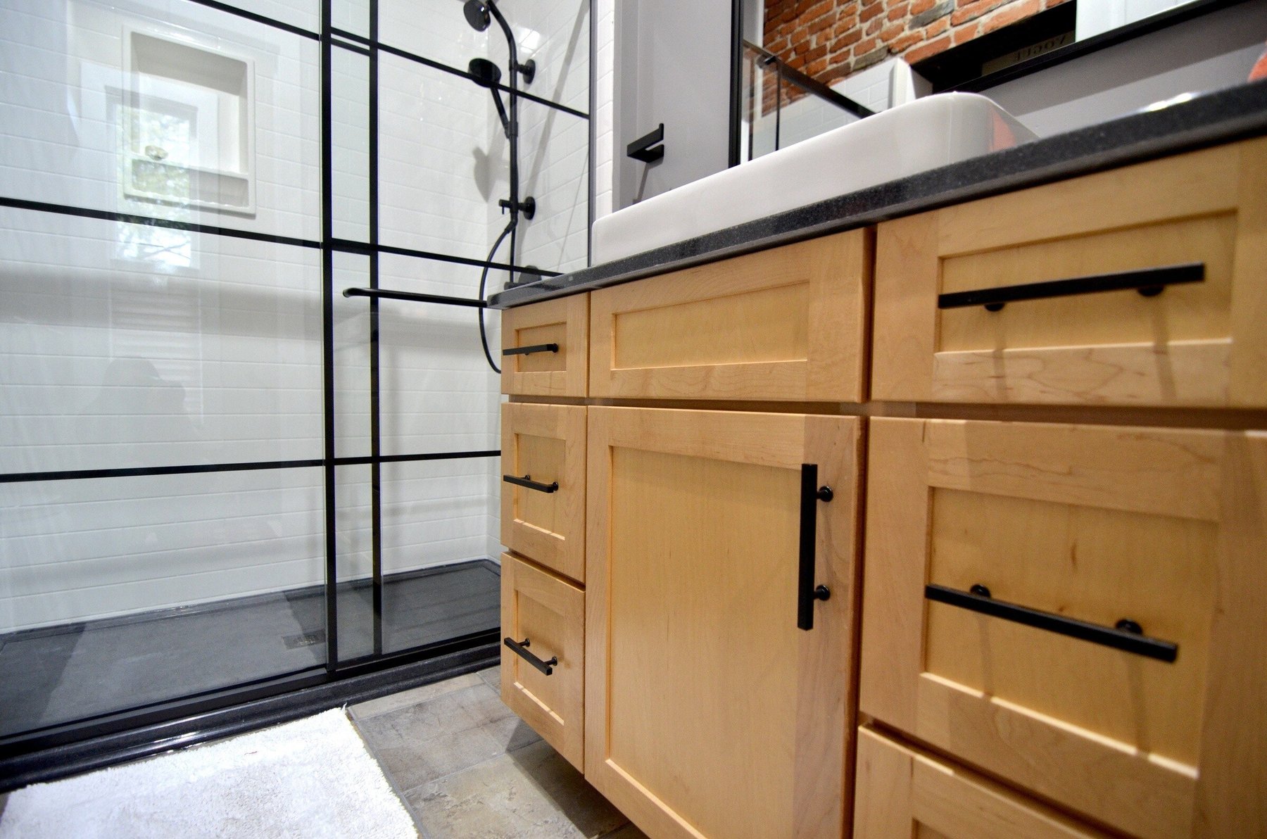 Bathroom with a black framed glass shower enclosure replacing an old tub